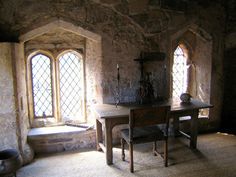 an old stone room with two windows and a table