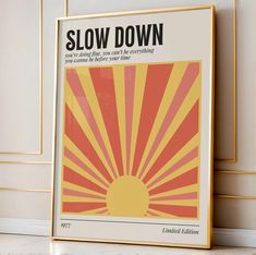 a yellow and red poster with the words slow down on it in front of a white wall