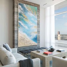 a living room filled with furniture and a painting hanging on the wall above a coffee table