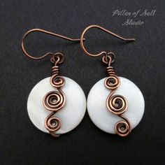 two white and copper swirls are on top of a pair of earwires