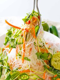 a salad with carrots, green beans and sprouts on a white plate