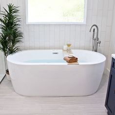 a white bath tub sitting in a bathroom next to a window