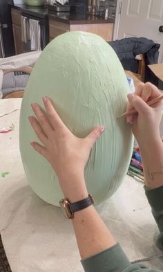 a woman is working on a large green object