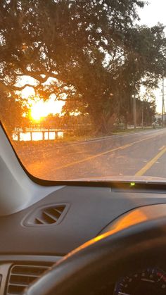 the sun is setting in the distance as seen from inside a car's dashboard