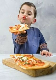 a young boy eating pizza from a cutting board