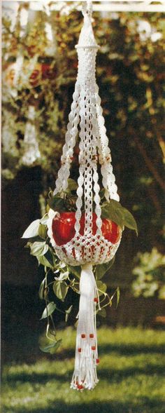 an apple hanging from a white macrame with leaves and flowers on it's side