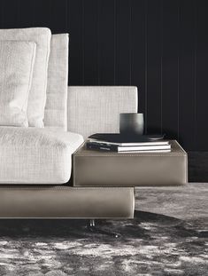 a white couch sitting on top of a rug next to a table with a book