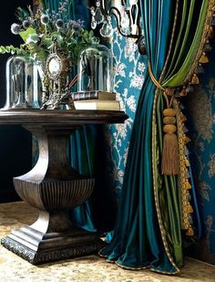 a table with vases on top of it next to a curtain