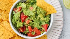 a white bowl filled with guacamole surrounded by tortilla chips