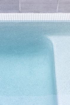 an empty swimming pool with tile flooring and blue water in the center, viewed from above