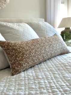 a bed with white and brown pillows on top of it