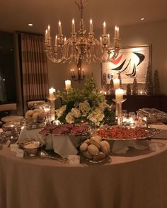 a table topped with lots of food next to a chandelier filled with candles