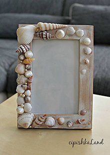 a wooden frame with seashells and shells around it on a table in front of a couch