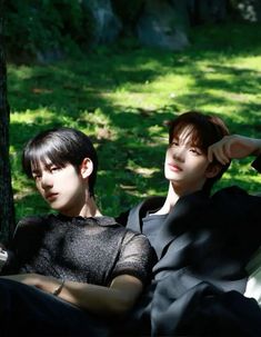 two young men sitting next to each other in the grass