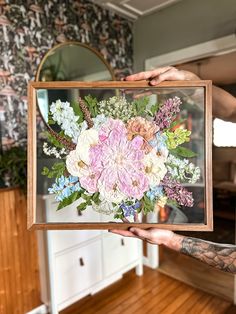 a person holding up a painting with flowers on it