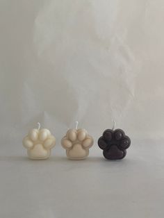 three candles with different colored paw prints on the top and bottom, one is black, one is white