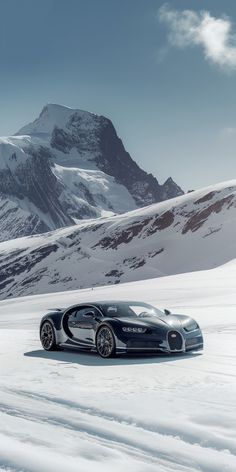 the bugatti veyron is driving on snow - covered ground with mountains in the background