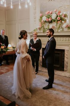 a bride and groom standing in front of a fireplace