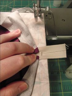 someone is sewing something on a piece of fabric with a sewing machine in the background