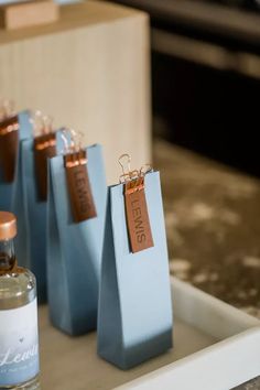 small blue bags with tags on them sitting on a tray next to a bottle of perfume