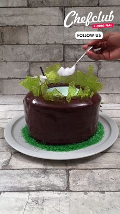 a chocolate cake with green leaves on top and a spoon sticking out of the icing