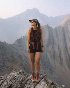 a woman standing on top of a rocky mountain