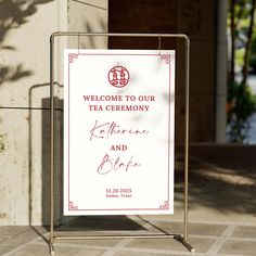 a welcome sign for the tea ceremony is posted on a metal stand in front of a building