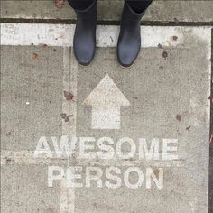 someone standing in front of a sign that says awesome person with an arrow on it