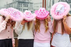 three girls wearing pink hats with hearts on them and one girl has her hair in the air