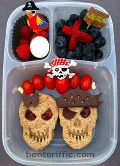 a plastic container filled with food and pirate themed decorations on top of each other's faces