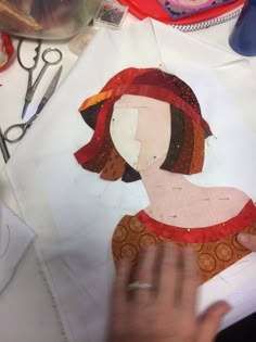 someone is cutting out a woman's face on paper with scissors and other crafting supplies