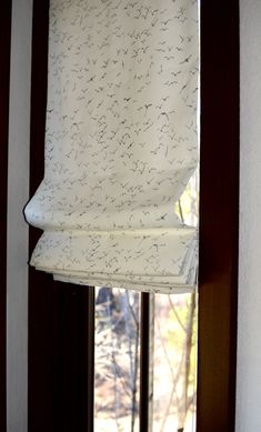 an open window with a white curtain hanging from it's side and the blinds pulled down