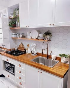 a kitchen with white cabinets and wooden counter tops