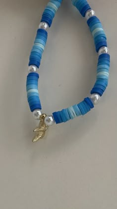 a blue and white beaded bracelet with a gold leaf charm on the clasp,