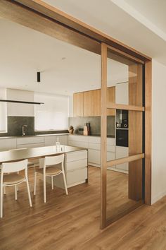 an open kitchen and dining area with wooden flooring, white walls and cabinets in the background