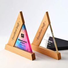 two wooden triangle shaped award plaques on top of each other in front of a white background