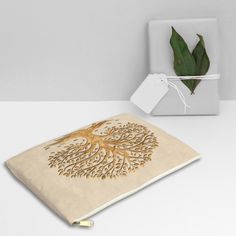 a white box with a golden tree design on it next to a gift wrapped in paper