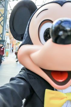 a person in a mickey mouse costume with a yellow bow tie and black jacket on