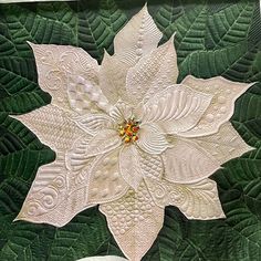 a quilted white poinsettia with green leaves on the bottom and yellow center