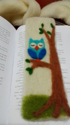 an owl bookmark is sitting on top of the open book, next to some yarn