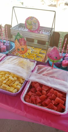 there are many trays of food on the table with strawberries and watermelon