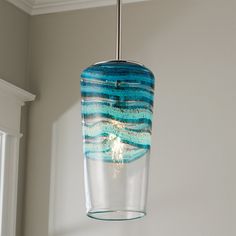 a blue and white glass light hanging from a ceiling