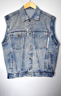 "Vintage 90's blue acid-wash denim vest. Straight collar. Has one half of zippers on each sleeve so it must've been a jacket once. Closes by the front snap buttons. Has two upper side flap pockets and two lower side welt pockets. There are also two large secret pockets on the inside. There is a cool applique front to the left featuring the brand and some national flags. Has two snap-button straps on the side at the bottom hem by which circumference can be adjusted by a choice of two options. Made in Italy. Brand: Utah Jeans Material: 100% cotton Size: tagged size 34DE, which corresponds to size 6US/8UK. For a best fit, please refer to the measurements below. Appr. Measurements (taken with vest lying flat, please double armpit to armpit, waist and bottom hem): shoulder seam to shoulder seam Cheap Y2k Denim Vest For Summer, Cheap Fitted Vintage Denim Jacket, Trendy Light Wash Vest For Fall, Trendy Medium Wash Vest, Winter Streetwear Distressed Denim Vest, Trendy Washed Denim Vest, Trendy Fitted Light Wash Vest, Fitted Grunge Vest For Fall, Distressed Medium Wash Denim Vest For Winter