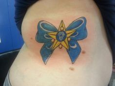 a woman's stomach with a blue and yellow ribbon tattoo on her side belly