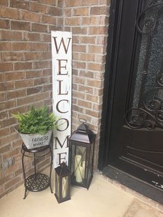 a welcome sign next to two lanterns and a potted plant