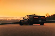 a black sports car driving down the road at sunset