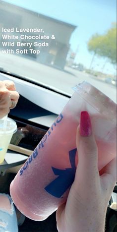 someone holding up a plastic cup with liquid in it and the words iced lavender, white chocolate & wild berry soda