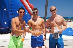 three men standing next to each other in front of an inflatable ball at the beach