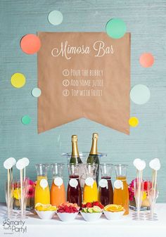 a table topped with bottles of drinks and glasses filled with fruit next to a sign that says mimosa bar