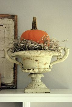 a white vase with a pumpkin sitting on top of it